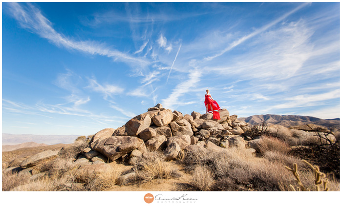 Desert inspiration session of a woman on a rock formation in a flowy red dress. Palm Desert, CA by Ann Keen Photography