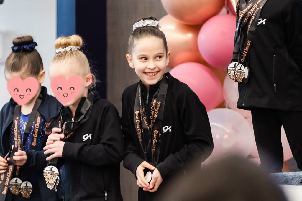 Blog:  Young gymnast all smiles after receiving her medals at a gymnastics meet