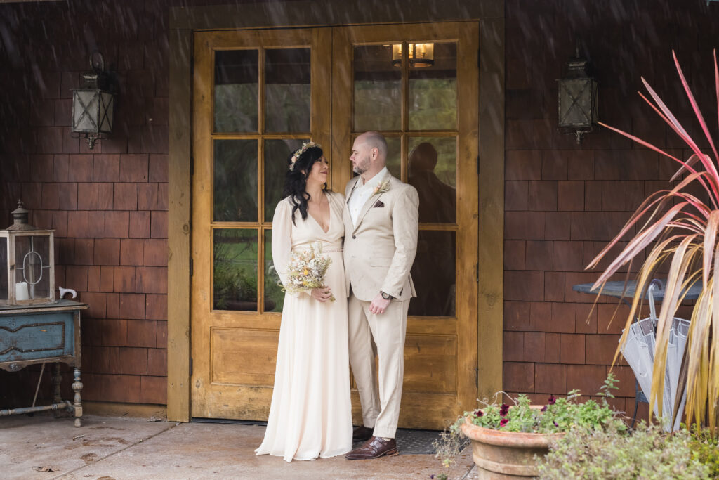 Scott & Eren, beautiful couple on their wedding day sheltered from the rain at the Newcastle Wedding Gardens in Newcastle, CA by Ann Keen Photography