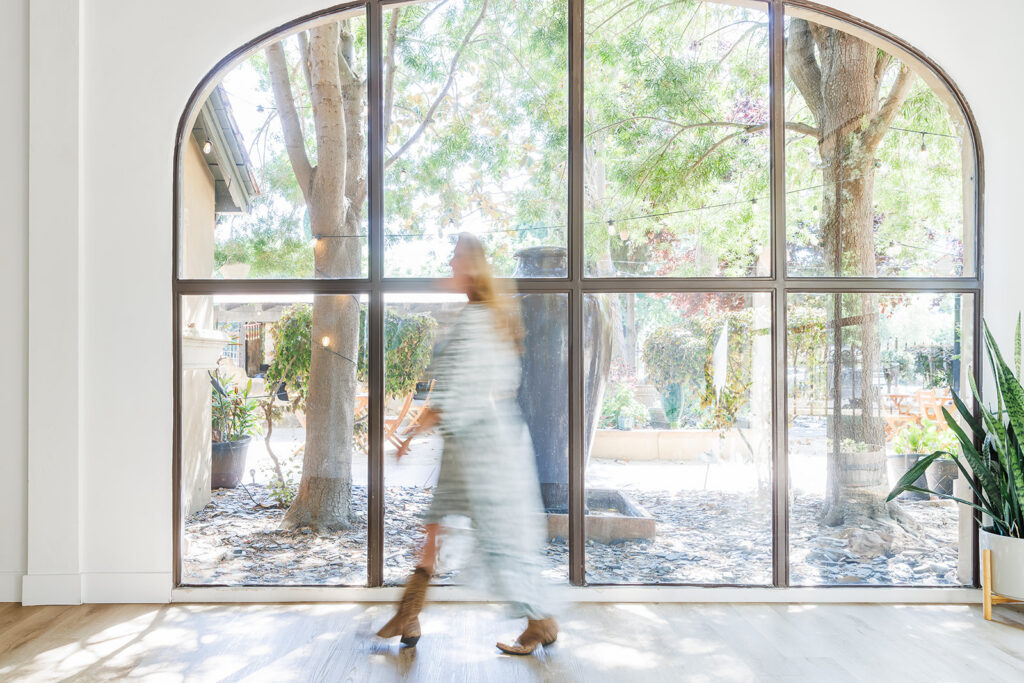Brand photography session in Folsom CA with Essential Key Hypnotherapy at the Mind Garden Folsom. Image is of business owner walking through business.