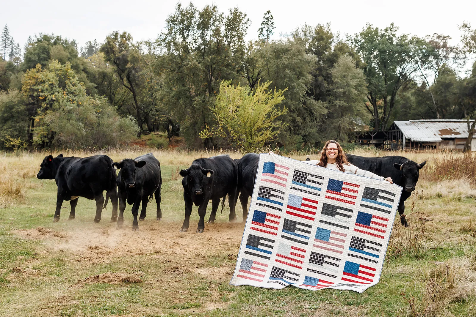 American flag quilt being held by owner Kayla Leal with cows from brand session in Auburn CA
