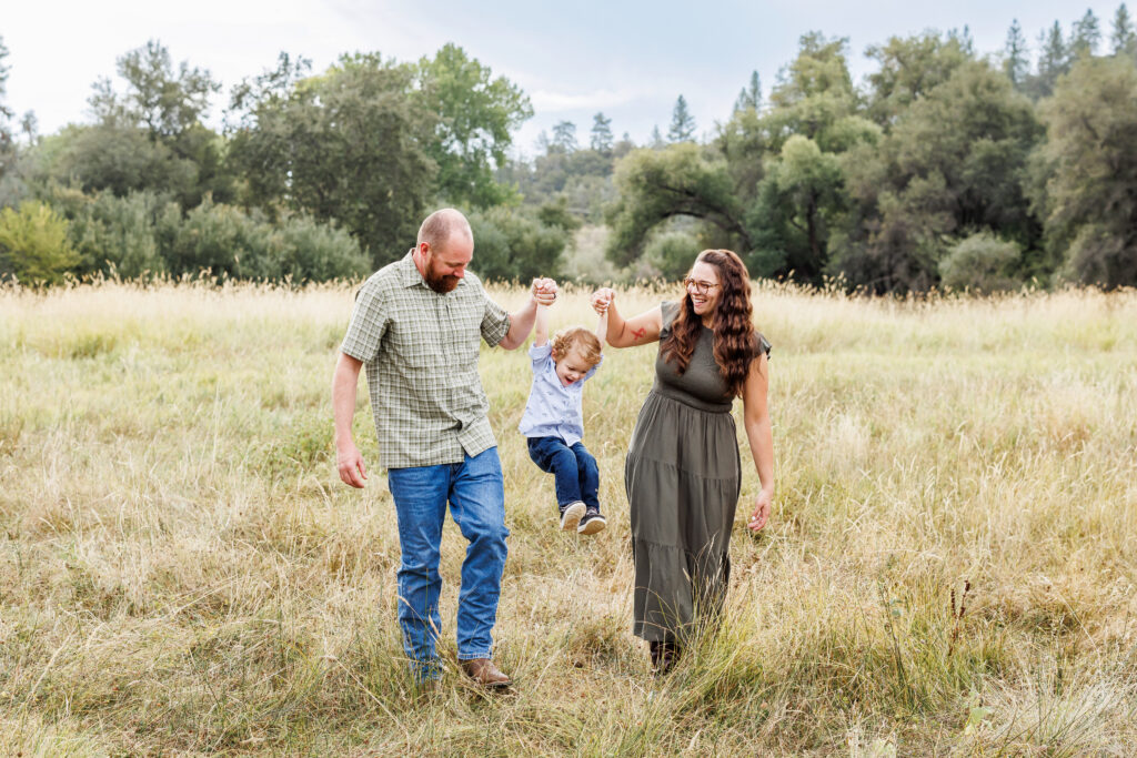 Family session on a farm in the morning.  Family of 3 swinging their kid while walking in Auburn, CA taken by Ann Keen Photography. What to wear.