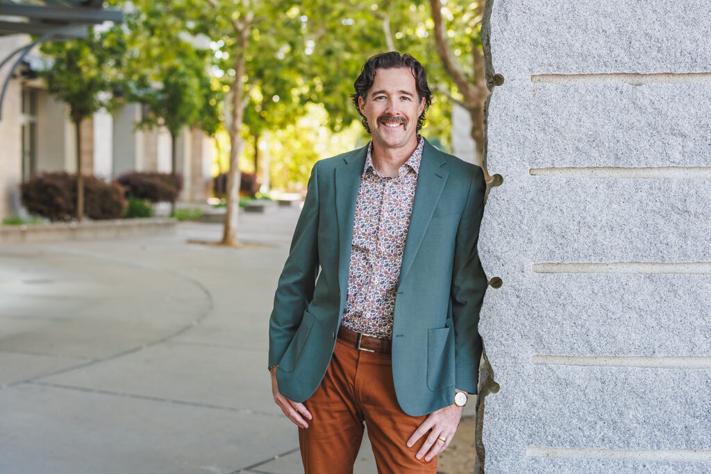 Brand Photography/Headshot of man in green blazer leaning on a post by Ann Keen Photography in Roseville, CA